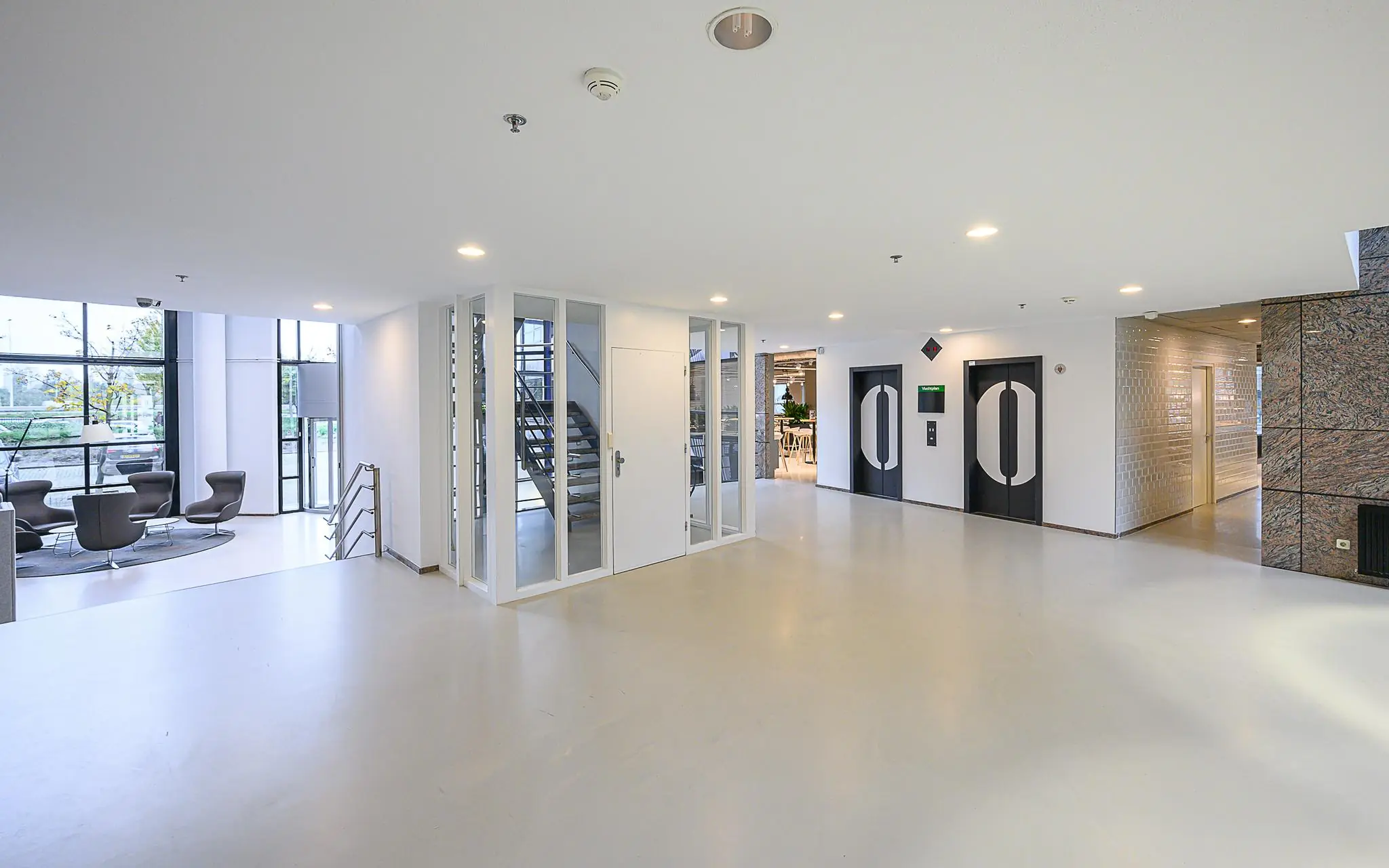 Moderne en lichte ontvangsthal van het Rivium Quadrant met zitgedeelte, trappenhuis en liften.